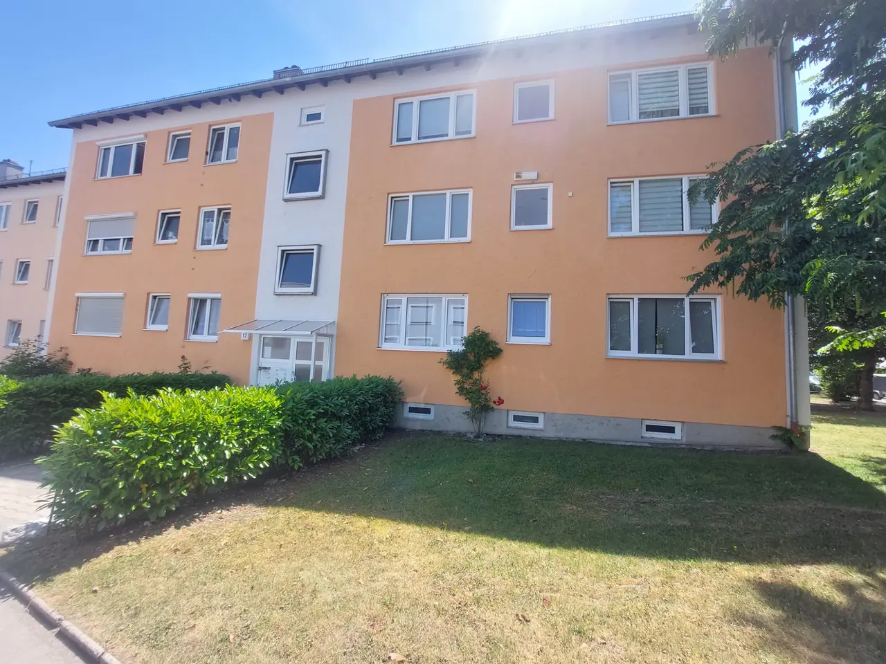 Dreigeschossiges Mehrfamilienhaus mit orangefarbener Fassade und Rasenfläche in Kaufbeuren, Referenzobjekt 07